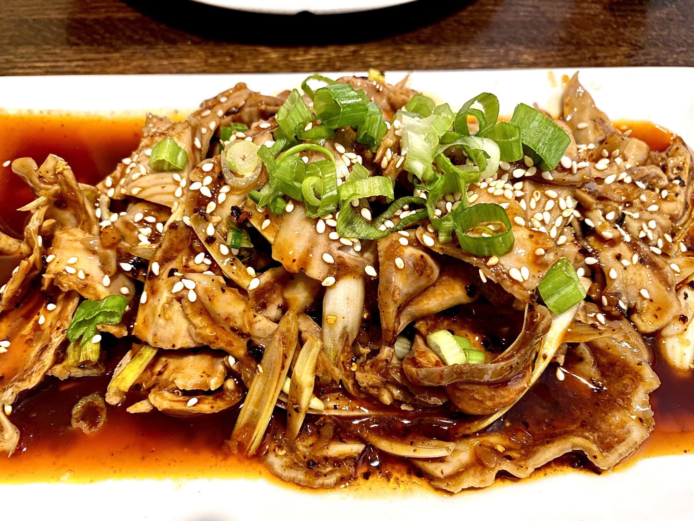 Wok-fried Sichuan dish finished with scallions and sesame